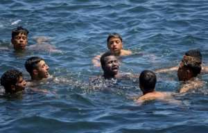 Young Moroccans come to the assistance of a migrant from sub-Saharan Africa as they attempt to swim past the land border with the Spanish enclave of Ceuta.  By FADEL SENNA (AFP)