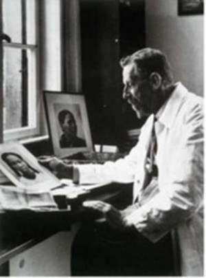 The evil Dr. Eugen Fischer whose pseudo-scientific theories of racial purity were practised on Namibians, at his desk with photos of African women.