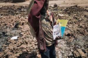 A child salvages school books from the Drodro camp for displaced people. The camp was devastated by militiamen last month. By ALEXIS HUGUET AFP
