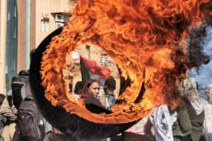 A demonstrator looks on from behind a flaming tyre at a makeshift barricade erected during a protest demanding civilian rule, in the Sudanese capital's twin city of Omdurman on January 4, 2022. By - AFPFile