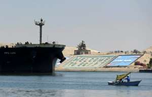A file photo taken on May 27, 2021 shows a small boat sailing in front of a ship in Egypt's Suez Canal. By Ahmad HASSAN AFPFile