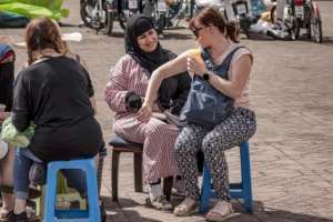 A henna tattoo artist draws on a tourist's arm in Jemaa el-Fnaa square in Marrakesh. By FADEL SENNA AFP