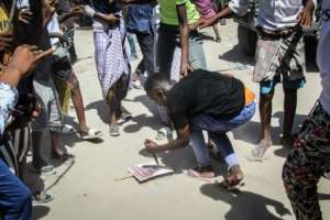 A man sticks a knife into a poster of Somalia's then president, Mohamed Abdullahi Mohamed, during the violent protests in Mogadishu in February 2021. By - AFP