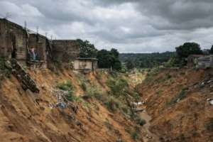 A woman and a boy look through the collapsed wall of a house after a landslide in Kinshasa. By ALEXIS HUGUET AFP