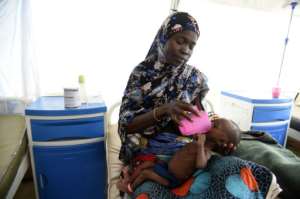 A woman at an MSF malnutrition clinic feeds the child of her late sister. By PIUS UTOMI EKPEI AFP