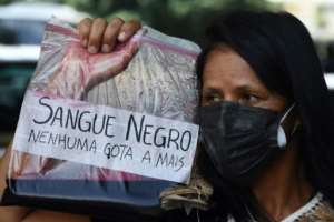 A woman holds a bag with mock blood that reads Black Blood, not one more drop during an anti-racism protest after Moise Kabagambe's killing. By EVARISTO SA AFPFile