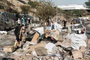 Community members clean up debris in the aftermath of looting. By RAJESH JANTILAL AFPFile