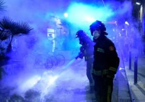 Firefighters put out a fire after a demonstration against a curfew in Barcelona as virus cases spike around Europe. By Josep LAGO AFP