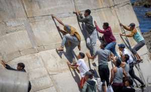 Migrants climb a sea wall in the northern town of Fnideq after attempting to cross the border from Morocco to Spain's North African enclave of Ceuta on May 19, 2021. By FADEL SENNA AFPFile