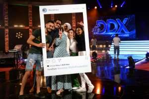 Participants pose for a photo with a cutout frame depicting an Instagram social media post on the set of the DDX talent show. By SOFIENE HAMDAOUI AFP