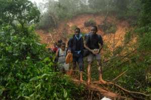 School students rescued by the Zimbabwean armed forces in Chimanimani walk past a mudslide caused by pounding rain. By ZINYANGE AUNTONY AFP