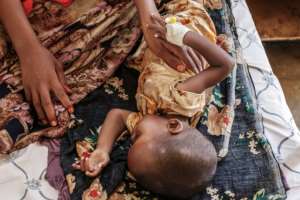 Small comfort: Mother Rukiyo Adan Mahad cuddles her sick daughter Samyia at the nutrition unit of the Gode General Hospital. By EDUARDO SOTERAS AFP