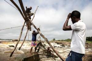 Wooden poles are wedged into holes in the rocks and tied together with lianas to form scaffolds. Baskets are then dropped from the scaffolding into the roaring currents to trap fish. By Guerchom Ndebo AFP