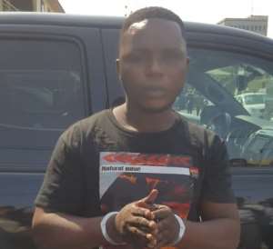 Suspect Emmanuel Owusu, standing by the stolen car