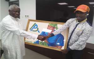 Mr. Fred Oware left receiving an art work from an official of the Ambassador Pamela Bridgewater Project