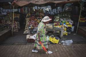 A woman walks past a market stall in Kliptown, Soweto. - Source: