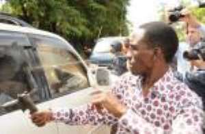 Gilbert Aranwaite, a Museveni government operative uses his gun to smash the window of car carrying Dr. Besigye. Photo credit: The Daily Monitor