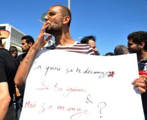 A protester in Tunis openly smokes a cigarette and holds a placard reading in French Why does it bother you if you fast and I eat? during Ramadan on June 11, 2017.  By Sofienne HAMDAOUI AFP