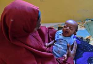 Ubah Mohamed Ali, 30, holds her 3 month old son Mohamed who is suffering from pneumonia, at the SAACID stabilization centre in Mogadishu.  By Carl de Souza AFP
