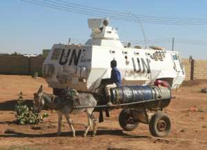 A boy rides a donkey cart as he looks at an armoured personnel carrier belonging to UNAMID in Abu Shok camp, in al-Fasher on December 16, 2013.  By Ashraf Shazly AFPFile