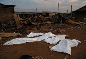 Dead bodies covered in plastic lie in front of a burnt out marketplace in Bor on February 1, 2014.  By Carl De Souza (AFP)