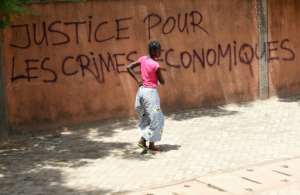 A woman walks past a wall with graffiti reading Justice for the economic crimes in Ouagadougou on October 1, 2015.  By Sia Kambou AFPFile