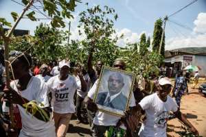 Supporters wave branches and hold a portrait of Burundian President Pierre Nkurunziza as they celebrate his return after a failed coup on May 15, 2015.  By Jennifer Huxta AFP