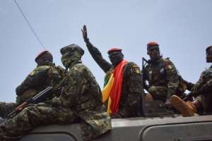 Coup leader Lieutenant Colonel Mamady Doumbouya, centre, waving to the crowd as he arrived at parliament on Monday for a meeting with outgoing ministers.  By CELLOU BINANI AFP