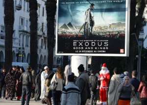 A man dressed as Santa Claus stands next to a billboard for the Hollywood biblical film Exodus: Gods and Kings in Rabat, Morocco, on December 26, 2014.  By Fadel Senna AFP
