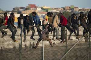 Would-be immigrants sit atop a border fence separating Morocco from the north African Spanish enclave of Melilla on October 22, 2014.  By Blasco Avellaneda AFPFile