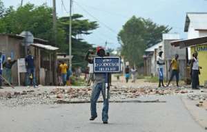 A protestor opposed to Burundian President Pierre Nkurunziza's third term holds a road sign reading Avenue of Democracy during a demonstration in the Buyenzi neighborhood of Bujumbura on May 26, 2015.  By Carl de Souza AFPFile