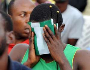 A Nigeria fan covers his face with the country's green and white flag as he watches the 2014 FIFA World Cup round of 16 football match between France and Nigeria at a viewing centre in Lagos on June 30, 2014.  By Pius Utomi Ekpei AFPFile