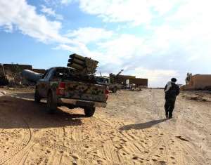 A fighter of Libya's Fajr Libya group walks past a truck mounted with a missile launcher in the hill village of Kikla, southwest of Tripoli, on October 21, 2014.  By Mahmud Turkia AFPFile