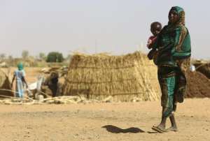 A Sudanese woman carries a baby at the Zamzam camp for Internally Displaced People IDP, North Darfur, on April 9, 2015.  By Ashraf Shazly AFP