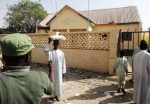 A street vendor passes by a partially burnt police station in the northern Nigerian city of Kano on January 25, 2012.  By Aminu Abubakar (AFP/File)