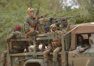 Malian soldiers patrol aboard a vehicule mounted with a machine gun in a street of Diabaly on January 26, 2013.  By Eric Feferberg AFP