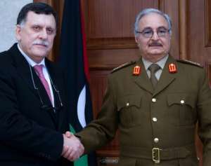 General Khalifa Haftar R, commander of the armed forces loyal to the internationally recognised Libyan government, shakes hands with the head of the UN backed Libyan Presidential Council, Fayez al-Sarraj, in the eastern town of al-Marj in 2016.  By  LIBYAN ARMED FORCES MEDIA OFFICEAFPFile