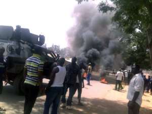 An armour vehicle parks behind a fire in Jos in March.  By  (AFP/File)