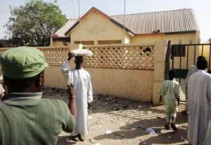 A street vendor passes by a partially burnt police station in the northern Nigerian city of Kano on January 25, 2012.  By Aminu Abubakar AFPFile