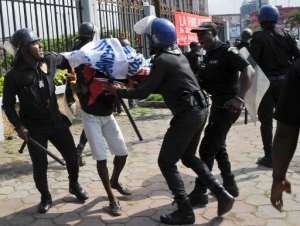 Ivorian police restrain a protester on November 25, 2014 in Abidjan, as people demonstrate against a ban to sell small plastic bags containing clean water.  By Sia Kambou AFP