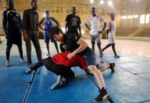 Japanese coach Kosuke Sunagawa R demonstrates a wrestling hold during his last training session in Khartoum.  By Ashraf Shazly AFPFile