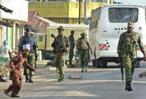 A Muslim schoolboy runs across a road past police officers on patrol around the Masjid Swafaa mosque in the Kisauni district in Kenya's coastal town of Mombasa following a raid on November 19, 2014.  By  AFPFile