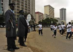 Police stand guard as participants take part in the Standard Chartered Marathon on October 30, 2011 in Nairobi.  By Tony Karumba AFPFile