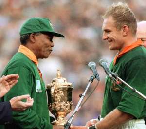 Nelson Mandela congratulates South Africa's rugby captain Francois Pienaar before handing him the Webb Ellis Cup in Johannesburg on June 24, 1995.  By Jean-Pierre Muller (AFP/File)