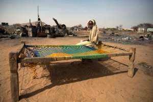 A displaced young girl sits on a makeshift bed in front of burnt houses in Kor Abeche, 83 km northeast on Nyala South Darfur on April 6, 2014.  By Albert Gonzalez Farran UNAMIDAFP