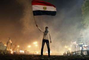 An Egyptian protester waves his national flag as he is surrounded by tear gas in Cairos Tahrir square, January 25, 2013.  By Mahmoud Khaled AFP