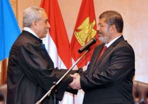 Egyptian President Mohamed Morsi (R) shakes hands with Faruq Sultan, head of the presidential election commission.  By  (Egyptian Presidency)