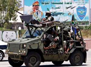 South African army soldiers patrol past a billboard with a picture of Moamer Kadhafi in Tripoli.  By Mahmud Turkia (AFP)
