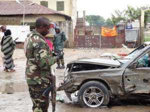 A soldier stands near a badly-damaged car at the scene of an explosion in Kano, northern nigeria on July 30, 2013.  By Aminu Abubakar AFPFile