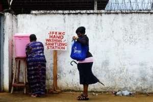 Women stop to clean their hands with sanitiser before entering the John Fitzgerald Kennedy hospital in Monrovia on September 1, 2014.  By Dominique Faget AFP
